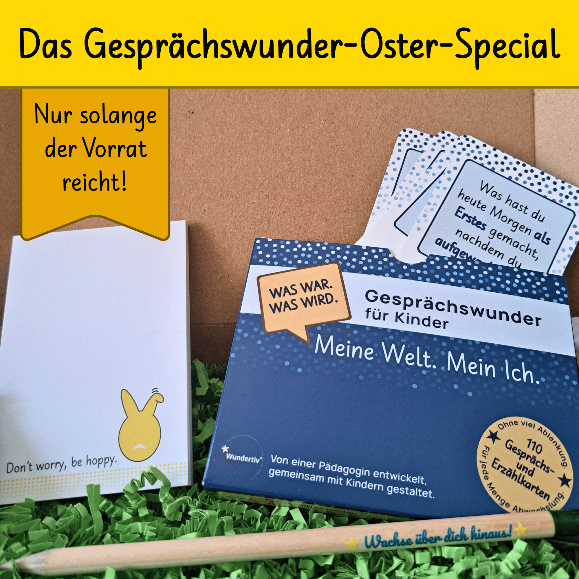 Osterspecial-Set in Box auf grünem Dekogras. Inhalt: Kartenset „Meine Welt. Mein Ich.“; Notizblock mit gelbem Hasen-Popo und Text „Don’t worry, be hoppy“; Holzbleistift mit graviertem Spruch „Wachse über dich hinaus!“.