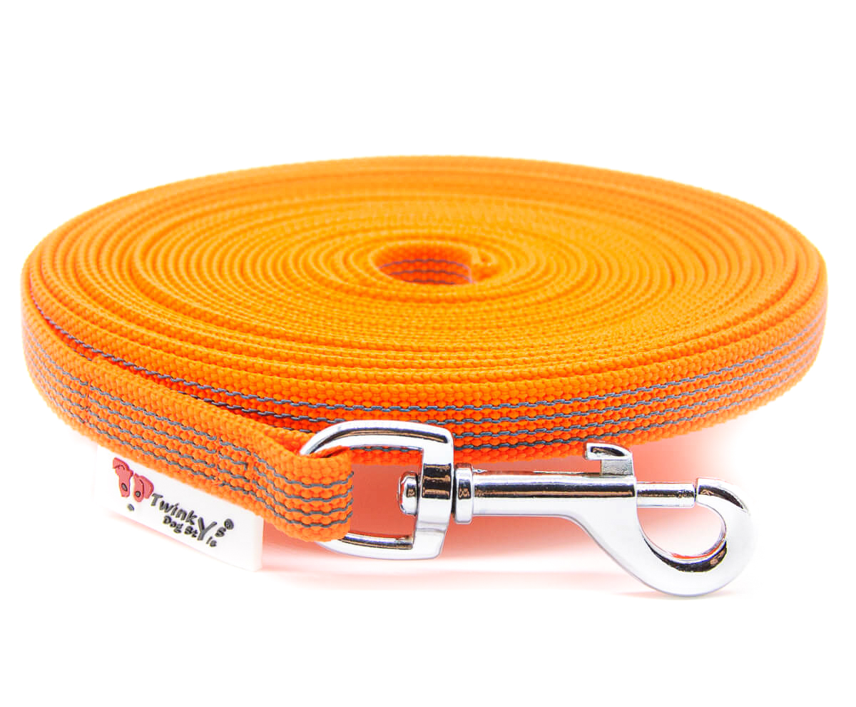 Orange gummierte Schleppleine in 15 mm Breite mit Zinkdruckgusskarabiner oder Edelstahlkarabiner, liegt aufgerollt auf weißem Hintergrund