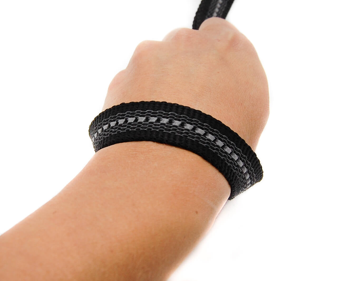 Handschlaufe einer schwarz reflektierend gummierten Leine um Handgelenk gelegt. Die Handschlaufe wird vorne von Hand festgehalten.