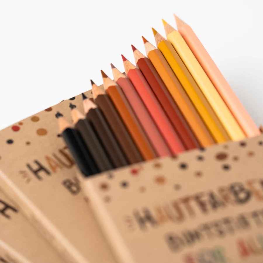 Detailbild eines Stapels mit Stiftverpackungen der Hautfarben Buntstifte auf weißem Hintergrund. Aus der oberen Verpackung ragen die Stifte etwas heraus