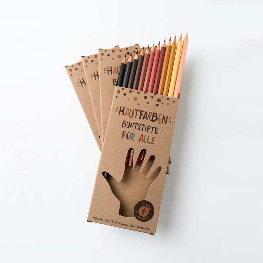 Ein Stapel mit Stiftverpackungen der Hautfarben Buntstifte liegen auf weißem Hintergrund. Die Aufnahme zeigt die Verpackungen liegend von Oben. Aus der oberen Verpackung ragen die Stifte etwas heraus